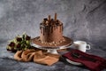 Chocolate Overloaded Cake with rose flowers, knife and fork served on board isolated on napkin side view of cafe baked food