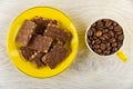 Chocolate pieces in saucer, coffee beans in cup on wooden table. Top view Royalty Free Stock Photo