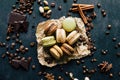 Chocolate pistachio coffee and vanilla flavored macaroons with pieces of chocolate cinnamon sticks coffee beans and pistachios Royalty Free Stock Photo