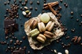 Chocolate pistachio coffee and vanilla flavored macaroons with pieces of chocolate cinnamon sticks coffee beans and pistachios Royalty Free Stock Photo