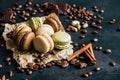 Chocolate pistachio coffee and vanilla flavored macaroons with pieces of chocolate cinnamon sticks coffee beans and pistachios