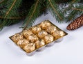 Chocolate pralines wrapped in gold foil with Christmas tree sprig Royalty Free Stock Photo