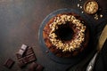 Chocolate and pumpkin bundt cake with chocolate glaze and walnut on dark concrete background. Selective focus. Top view. Copy