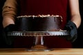 Chocolate raw cake with jam filling with hazelnuts on wooden table. vegan dessert closeup. woman confectioner hold chocolate cake Royalty Free Stock Photo