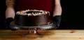 Chocolate raw cake with jam filling with hazelnuts on wooden table. vegan dessert closeup. woman confectioner hold chocolate cake Royalty Free Stock Photo