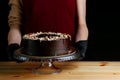 Chocolate raw cake with jam filling with hazelnuts on wooden table. vegan dessert closeup. woman confectioner hold chocolate cake Royalty Free Stock Photo