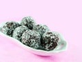 Chocolate rum balls covered with dessicated coconut powder in white porcelain dish