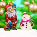 Chocolate Santa Claus in the snow with a cheerful snowman. Royalty Free Stock Photo