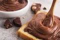 Chocolate spread on slice of bread with spoon, melted cream white bowl Royalty Free Stock Photo