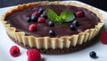 A chocolate tart with raspberries and mint leaves on top