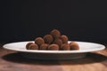 Chocolate truffle balls on white plate on wood table