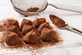 Chocolate truffles sprinkled with cocoa powder closeup. Delicious dark chocolate candy balls, mesh strainer and spoon over marble Royalty Free Stock Photo