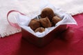 Chocolate truffles in tin box on red background with ribbon