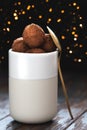 Chocolate truffles in a white cup on a wooden background. Front view.