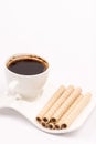 Chocolate wafer cream rolls and white cup of black coffee Royalty Free Stock Photo