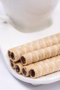 Chocolate wafer cream rolls and white cup of black coffee Royalty Free Stock Photo