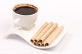 Chocolate wafer cream rolls and white cup of black coffee Royalty Free Stock Photo