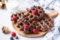 Chocolate waffles and berries on a wooden plate on a wooden baclground