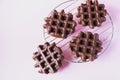 Chocolate waffles on a cooling rack. Top view, pink background