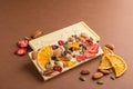 Chocolate white fruit whole tile decorated with slices of fruit nuts and slices on a brown background. Minimalism food Royalty Free Stock Photo