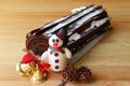 Chocolate Yule Log Cake or Buche de Noel Decorated with Snowman Marzipan and Dry Pine Cones, Christmas Ornament on Wooden Table Royalty Free Stock Photo