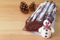 Chocolate Yule Log Cake for Christmas or Buche de Noel with a Cute Snowman Marzipan and Two Dry Pin Cones Royalty Free Stock Photo