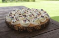 Chocolates decorated with white cream on a wooden plate on a rustic wooden table in the garden during a sunny day