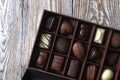 Chocolates in different shapes and colors in gift box on wooden table. Flat lay.