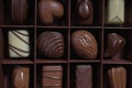 Chocolates in different shapes and colors in gift box on wooden table. Flat lay.