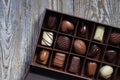 Chocolates in different shapes and colors in gift box on wooden table. Flat lay.