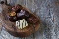 Chocolates in different shapes and colors over rustic wooden board.