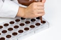 Chocolatier pouring praline filling into chocolate mold preparing belgium candy