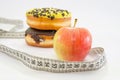 Choice between apple or junk food, donut. Diet and healthy food concept. Vegetarian, vegan,. Apple, measuring tape and donuts and Royalty Free Stock Photo