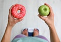 Choice concept. Top view of woman with apple and doughnut standing on scales, closeup Royalty Free Stock Photo