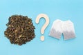 Choice between loose leaf green tea and tea bags. Wooden question mark. Blue background. Dried green tea leaves. Flat Royalty Free Stock Photo