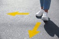 Choice of way. Woman walking to drawn mark on road, closeup. yellow arrows pointing in different directions Royalty Free Stock Photo