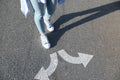 Choice of way. Woman walking towards drawn marks on road, closeup. White arrows pointing in opposite directions Royalty Free Stock Photo