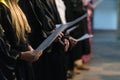 Choir singers holding musical score and singing on student graduation day in university, college diploma commencement Royalty Free Stock Photo