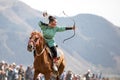 Female archer shooting an arrow on horseback.