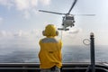 Helicopter deck officer give hand signal to Sikorsky S-70 Sea Hawk helicopter hovering above helicopter deck of Navy ship to