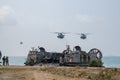 US Marine Corps Landing Craft Air Cushion or LCAC lands on the beach with Two CH-53 Sea Stallion heavy-lift transport helicopters Royalty Free Stock Photo