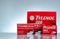 Tylenol 500 mg and Tylenol 8 hour 650 extended-release caplets in red packaging on gradient background. Drug for relief pain