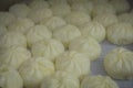 CHONGYUANG TEMPLE, CHINA: Small cakes of white raw dough, spread out in pot waiting to be deep fried, food market around