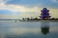 CHONGYUANG TEMPLE, CHINA: Temple tower in blue and pink color, sitting on land next to nice lake, peaceful morning mood
