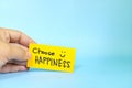 Choose happiness and be happy always reminder concept. Hand holding a bright yellow paper message