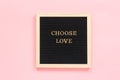 Choose love. Motivational quote in gold letters on black letter board on pink background, central composition . Top view Concept i