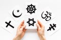 Choose religion concept. Hands with Jewish star of David near world religions symbols on white background top view