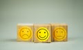 Choose square wooden block with a face grin emoticons. A survey, poll, or questionnaire based on user experience Royalty Free Stock Photo