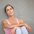 Choose your lifestyle. Portrait of an attractive mature woman in gymwear sitting against a gray wall.