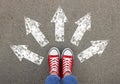 Choosing future profession. Girl standing in front of drawn signs on asphalt, top view. Arrows pointing in different directions Royalty Free Stock Photo